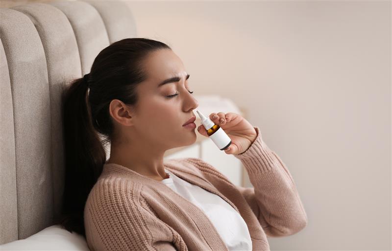 Una chica se está rociando con un spray nasal.